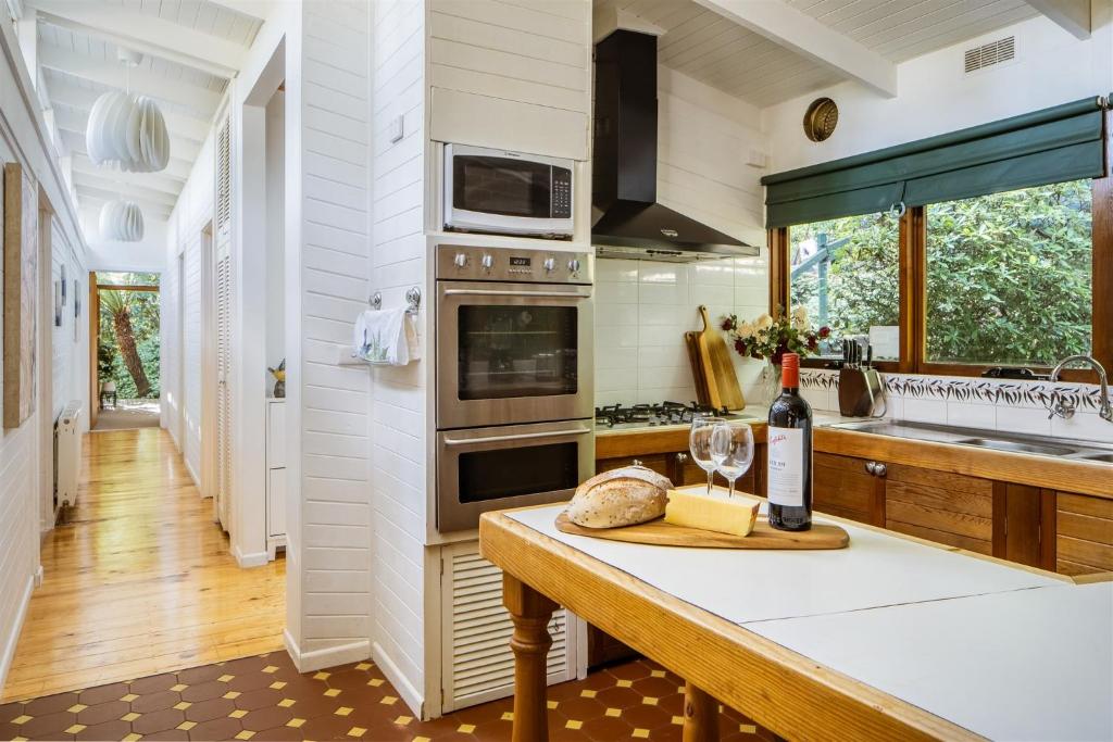 a kitchen with a table with a bottle of wine at Modern Seednest Treehouse, Forest & Mountain View in Sassafras
