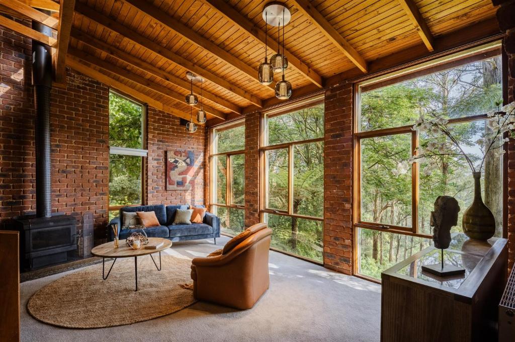 a living room with a couch and a table at Modern Seednest Treehouse, Forest & Mountain View in Sassafras