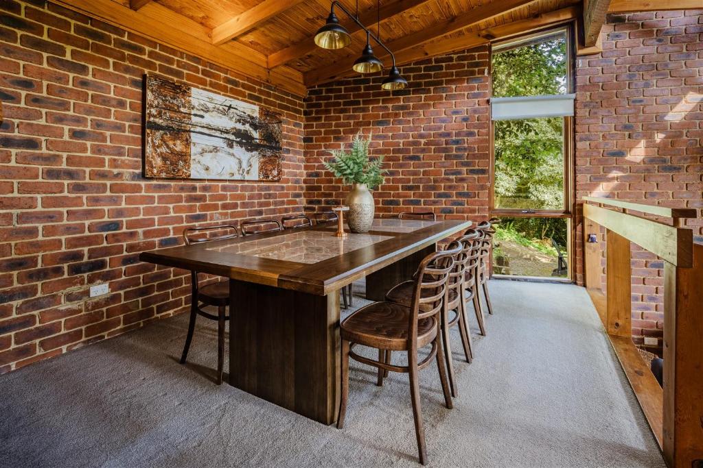 a kitchen with a large wooden table in a brick wall at Modern Seednest Treehouse, Forest & Mountain View in Sassafras
