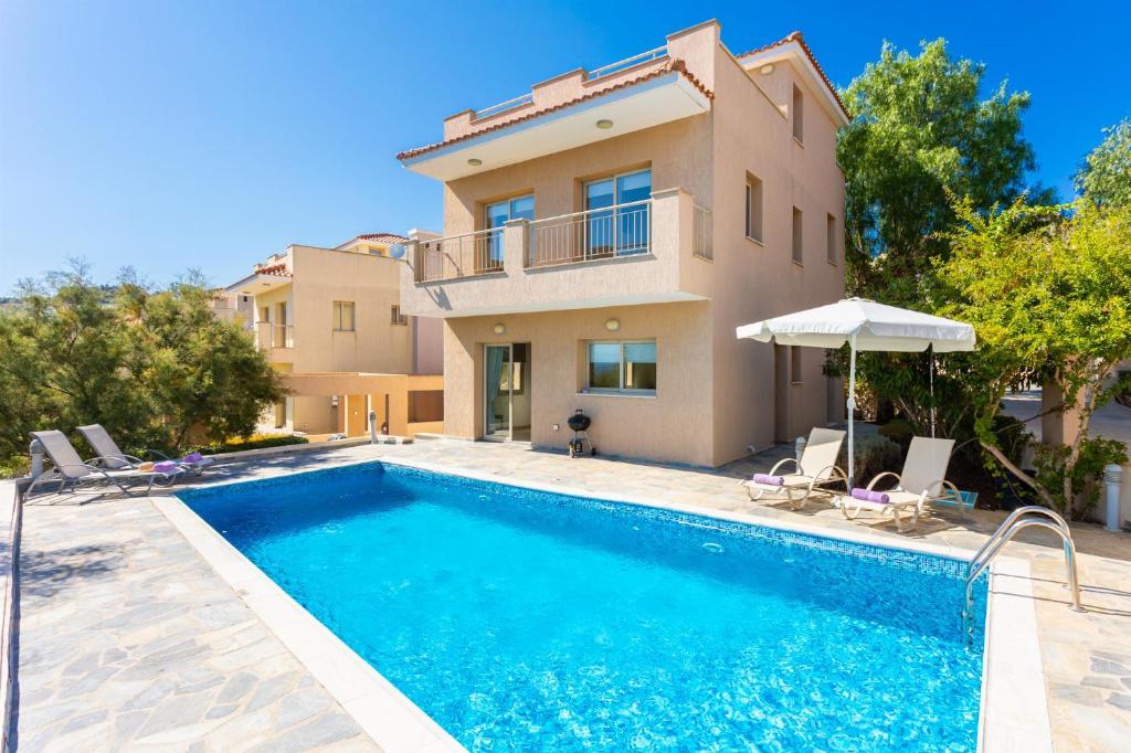 une villa avec une piscine en face d'une maison dans l'établissement Villa Panorama Tria, à Droushia