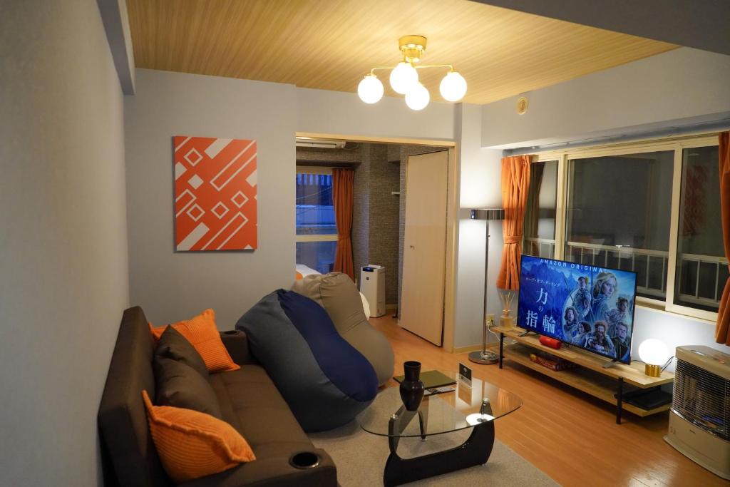 een woonkamer met een bank en een flatscreen-tv bij SAPPORO HILLS in Sapporo