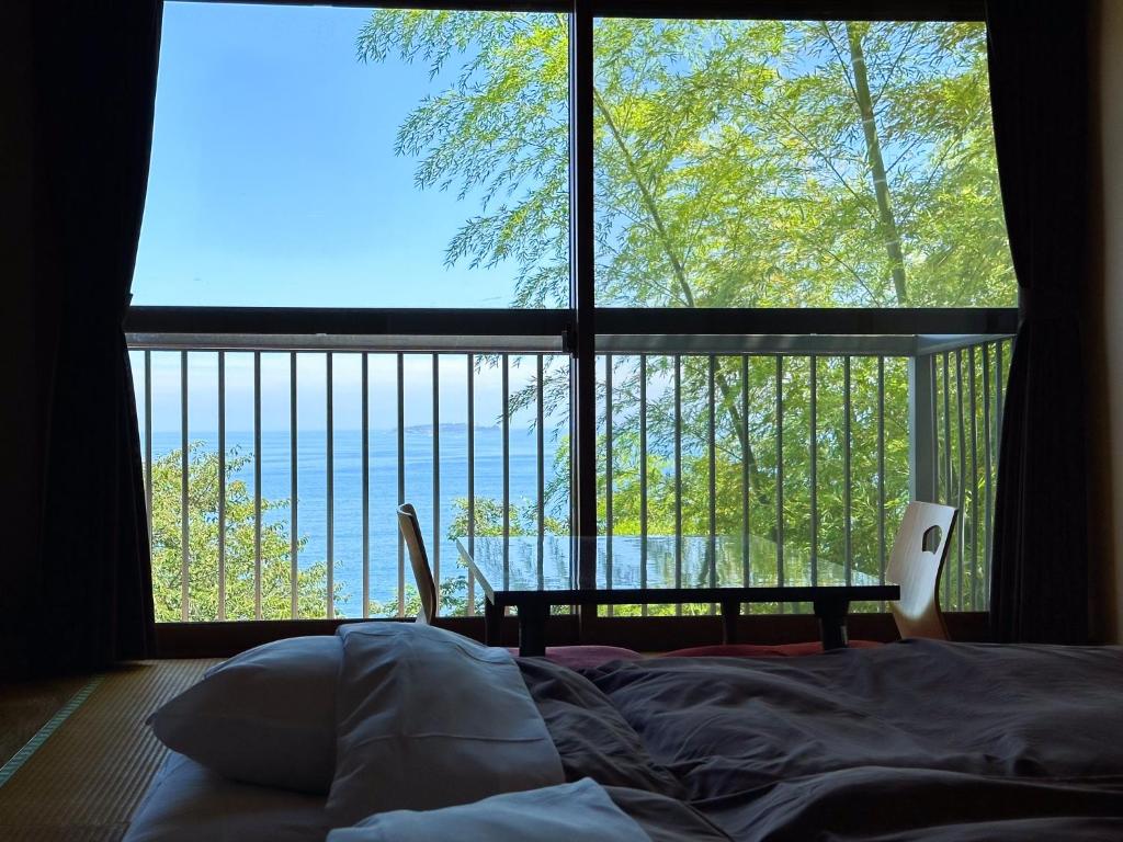 a bedroom with a large window with a view of the ocean at 123MUSIC(イズサンミュージック) in Atami