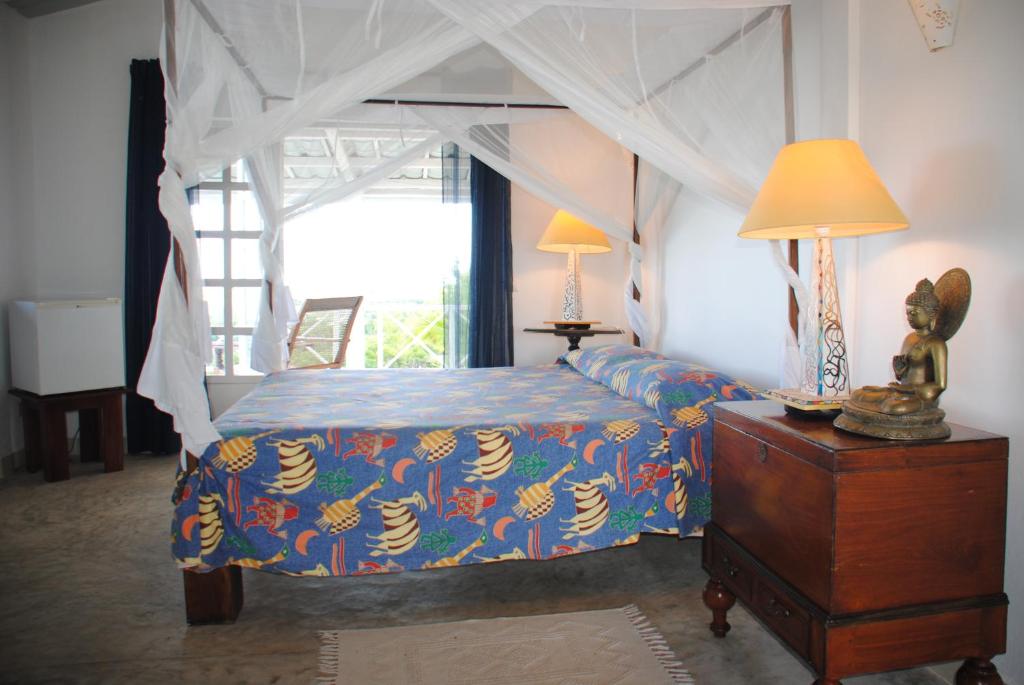a bedroom with a bed with a blue comforter at camera matrimoniale grande terrazza vista stupenda in Nosy Be