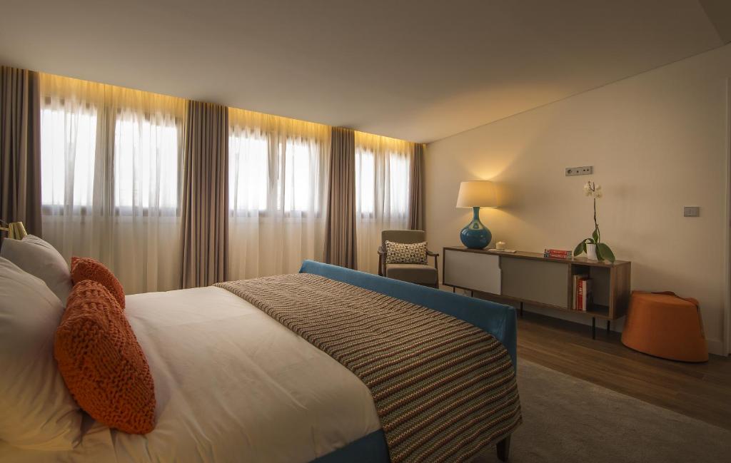 a hotel room with a bed and a chair and window at Somewhere - Estoril Guesthouse in Estoril