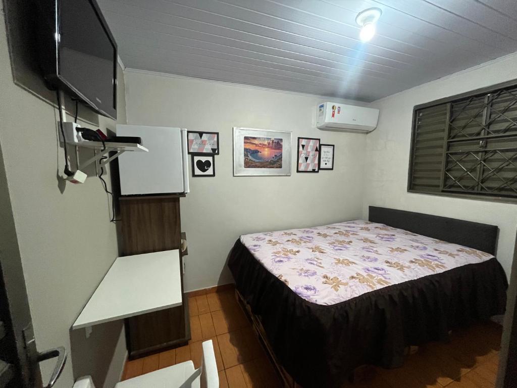 een slaapkamer met een bed en een flatscreen-tv bij Casa Recanto - Quarto simples in Rio Verde