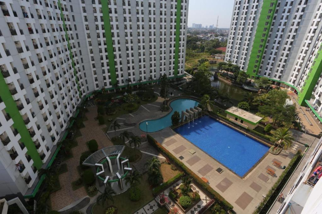 une vue sur la piscine au milieu de deux grands bâtiments dans l'établissement Capital O 93371 Pelangi Residence 5, à Tangerang