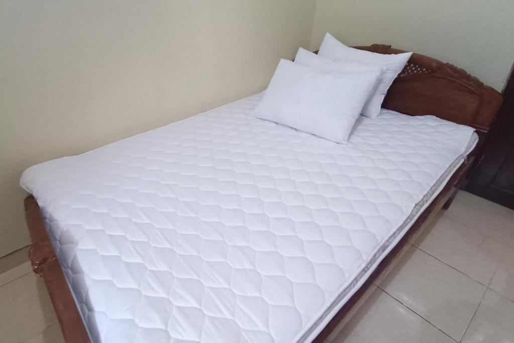 a bed with white sheets and pillows on it at SPOT ON 93376 Roemah Ambarrukma 185 Syariah in Yogyakarta