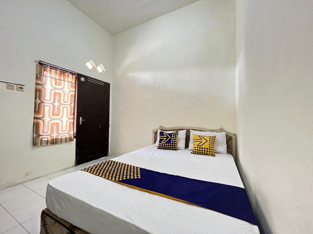 um quarto com uma cama num quarto com uma janela em SPOT ON 93398 Sudimoro Guest House Syariah em Blimbing