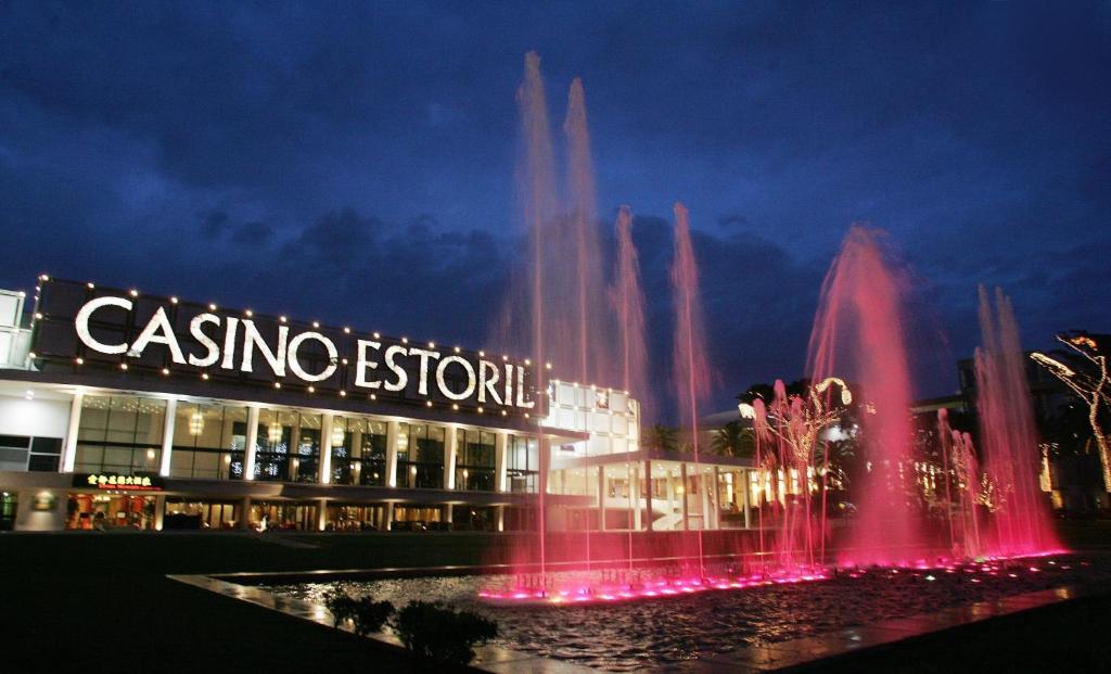 a fountain in front of a casino resort at night at Somewhere - Estoril Guesthouse in Estoril