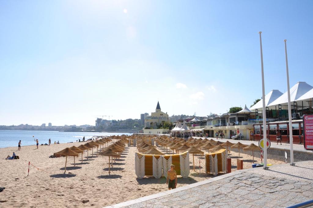 a beach with chairs and umbrellas and people on it at Somewhere - Estoril Guesthouse in Estoril