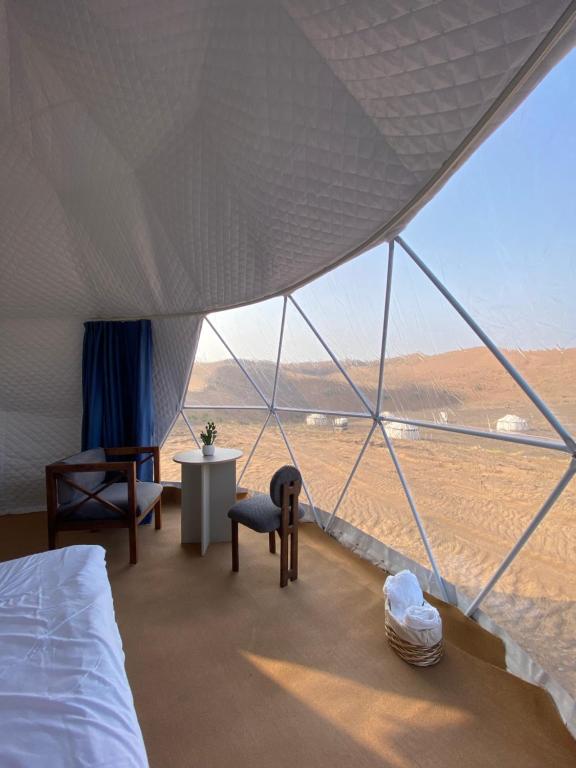 a bedroom with a bed and a view of the desert at Black Sand Camp in Muntarib