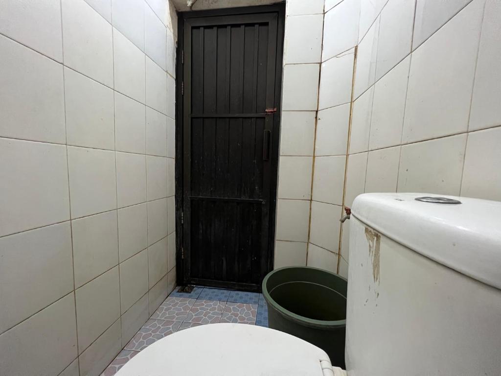 baño con aseo y puerta negra en OYO 93406 Pondok Bulo Ugi Syariah 
