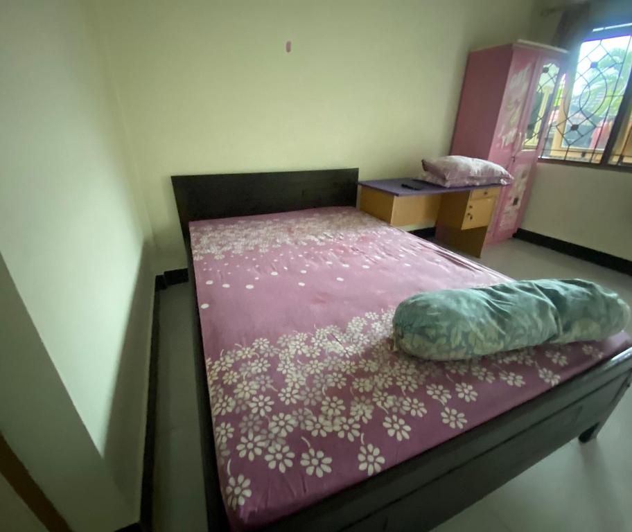 Cama pequeña en habitación con colcha púrpura en OYO Life 93407 Kos Sweta, en Tjakranegara