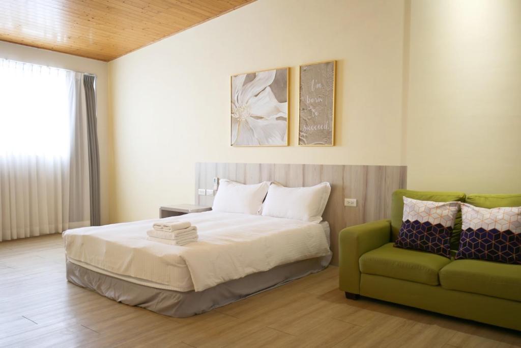 a bedroom with a bed and a green couch at Canal walk inn in Anping