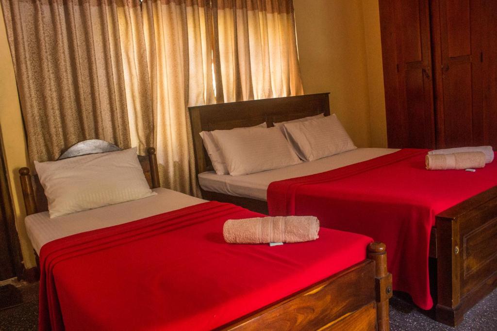 a bedroom with two beds with red sheets at Spice & Herb Rooms & Food in Kandy
