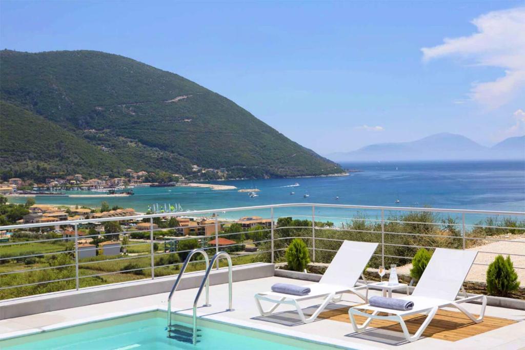 a pool with chairs and a view of the ocean at OFF White Villas in Vasiliki