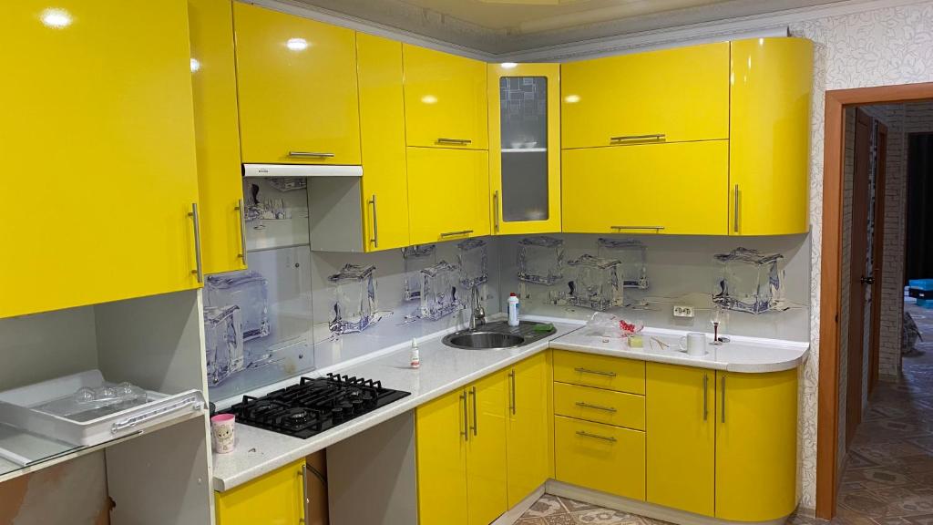 a kitchen with yellow cabinets and a sink at Квартира in Oral