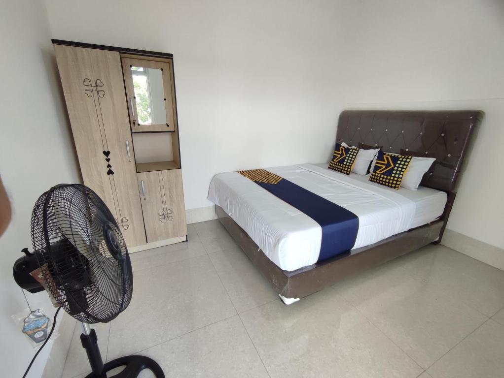 a bedroom with a bed and a fan in it at SPOT ON 93367 Wisma Sidosari Syariah in Lampung