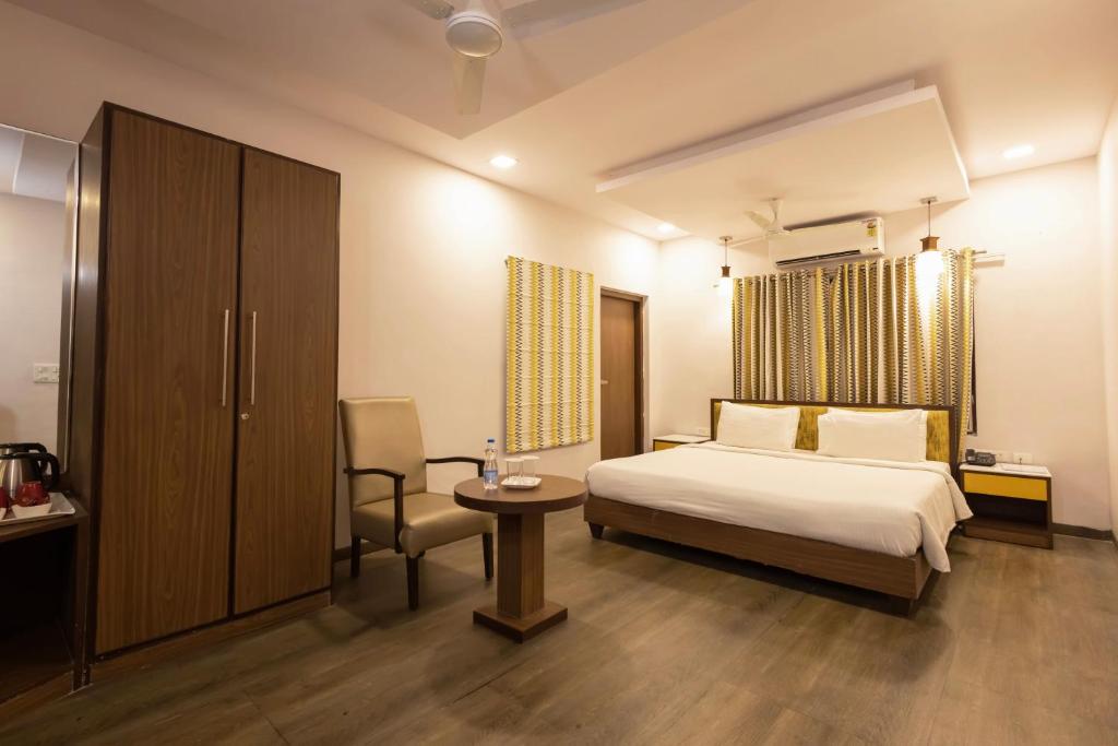een slaapkamer met een bed, een tafel en een stoel bij Classic Boutique Hotel & Luxury Service Apartments in Visakhapatnam