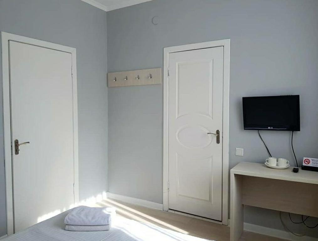 1 dormitorio con puerta blanca y TV en Sky hotel KG, en Bishkek