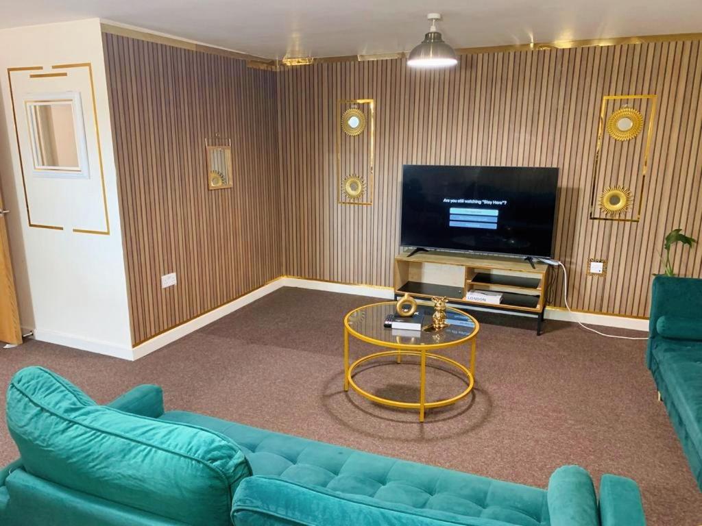 a living room with a blue couch and a tv at Jesse 2 Bedroom Apartment by GET in Dunstable