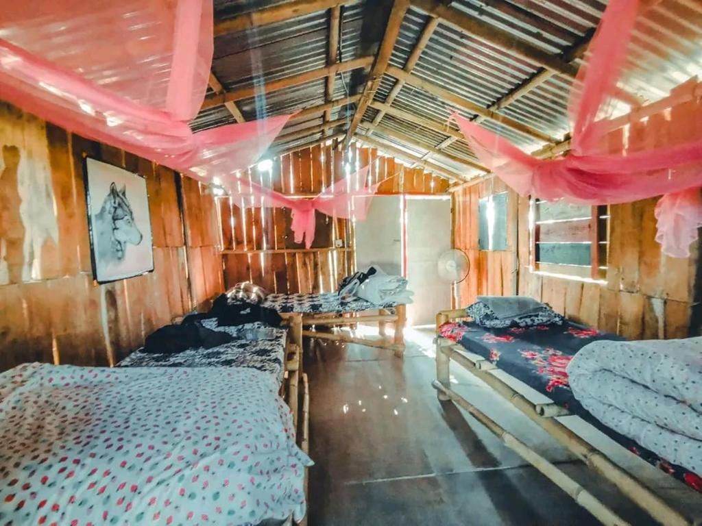 una camera con due letti e tende rosa di Pemsee's Tree Town - Eco-friendly,Tree house hostel a Sauraha