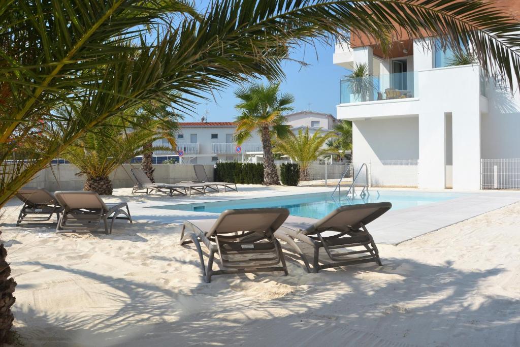 a group of chairs sitting next to a swimming pool at Sun Beach Residence con Piscina - Piazza Brescia - Adria Holiday Jesolo - FAMILY APARTMENTS in Lido di Jesolo