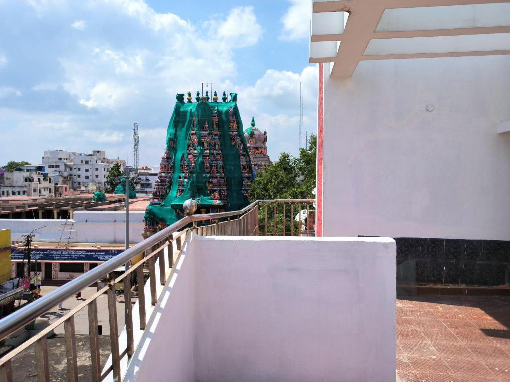 een persoon op een balkon met uitzicht op een groene structuur bij LA villa Rani in Madurai