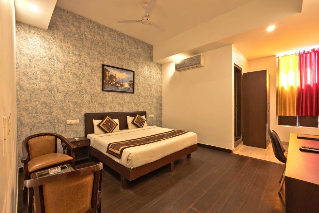 a bedroom with a bed and a desk in a room at Luxury Tashree Hotel at Airport in New Delhi