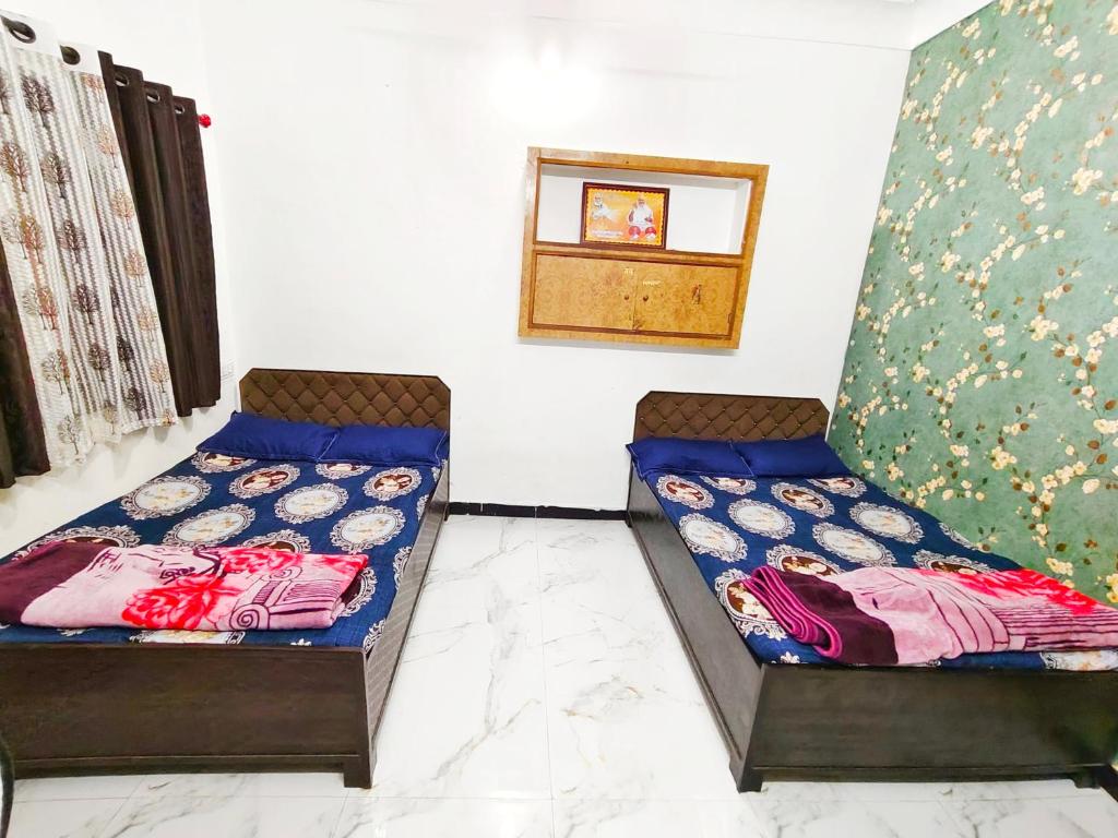two beds sitting next to each other in a room at Shivay homestay ujjain in Ujjain