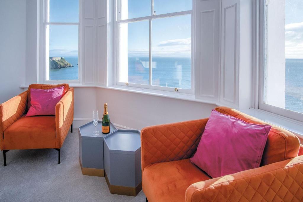 2 sillas y una mesa en una habitación con ventanas en Caldey View - Luxury 2 Bedroom - Panorama - Tenby, en Tenby