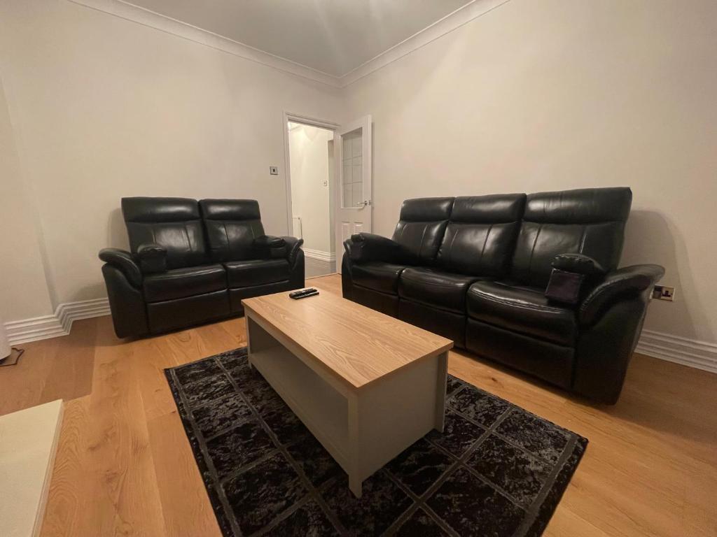 a living room with black leather furniture and a coffee table at Homely and very comfortable apartment in London