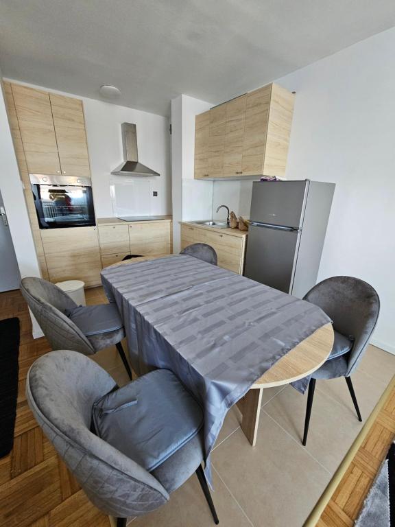 cocina con mesa, sillas y nevera en Apartman FITT en Zagreb