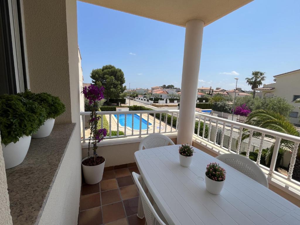 a white table on a balcony with a view of a pool at SA CALMA - Duplex con piscina y cerca del Mar - Deltavacaciones in L'Ampolla