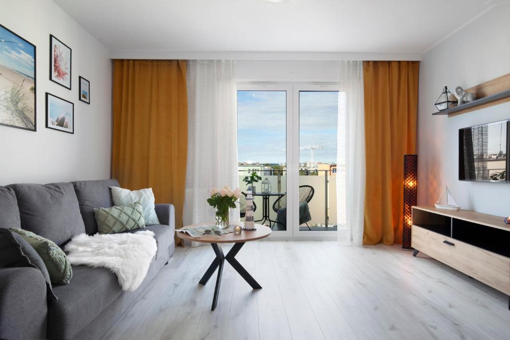 格但斯克的住宿－Elite Apartments Nadmorski Brzeźno，客厅配有灰色的沙发和桌子