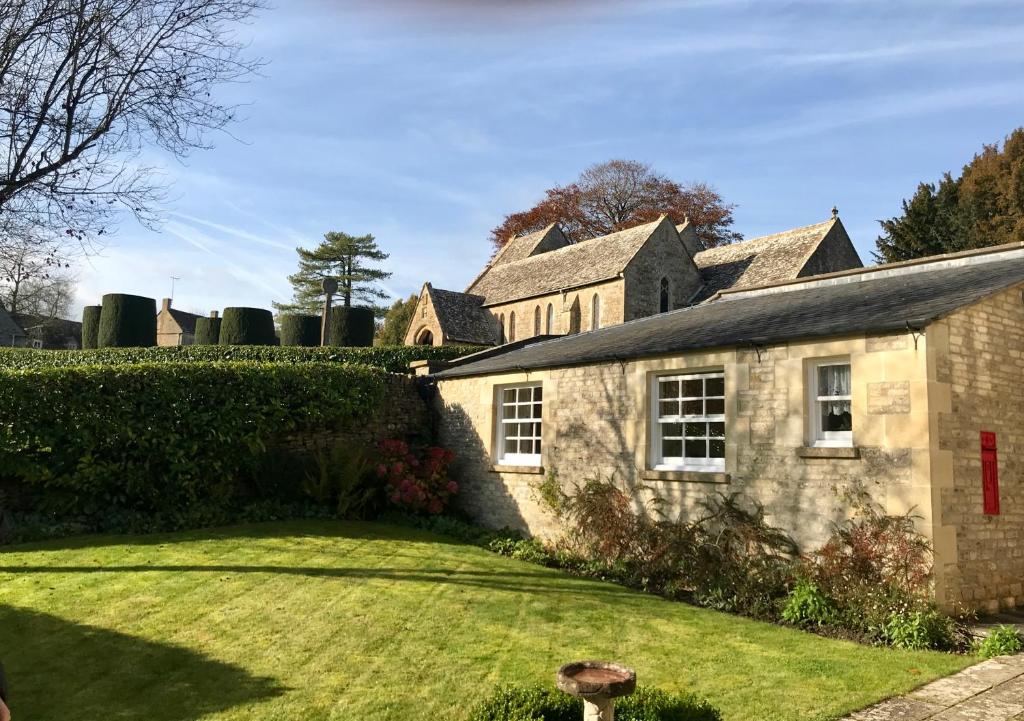 an old stone house with a yard at The Old Post Office Studio Apartment in a Beautiful Cotswold Village in Cirencester