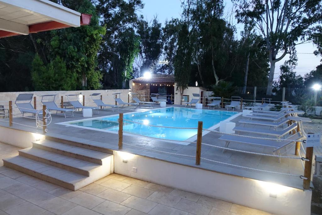 una piscina con sedie e tavolo e un edificio di Giardini Sausari Residence a Punta Prosciutto