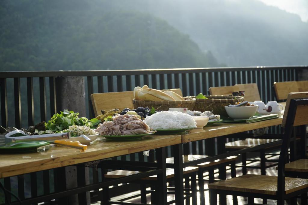 una mesa de madera con comida en el balcón en Nung Gia Homestay, en Xin Man