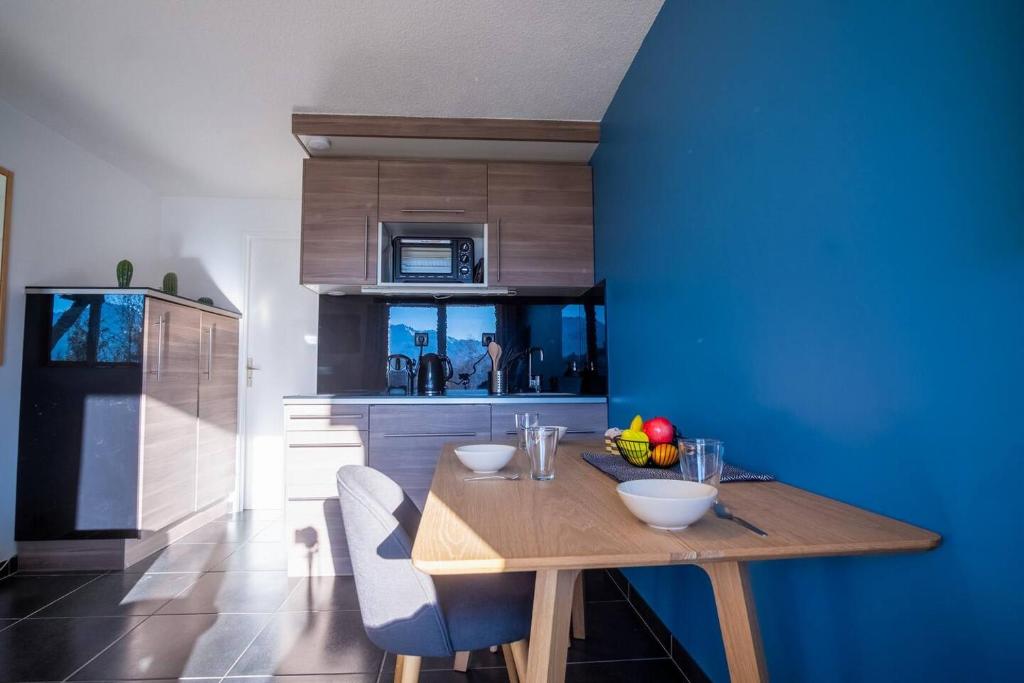 cocina con mesa de madera y pared azul en Studio Maona - skis au pied en Huez