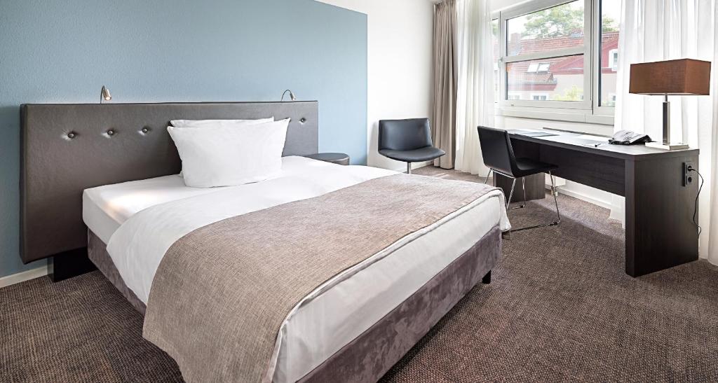 a hotel room with a bed and a desk and a desk at Victor's Residenz-Hotel Berlin Tegel in Berlin