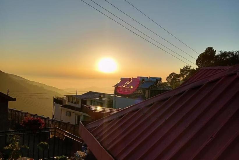 een uitzicht op de zonsondergang vanaf een dak van een huis bij SANDAL HOMESTAY in Kasauli