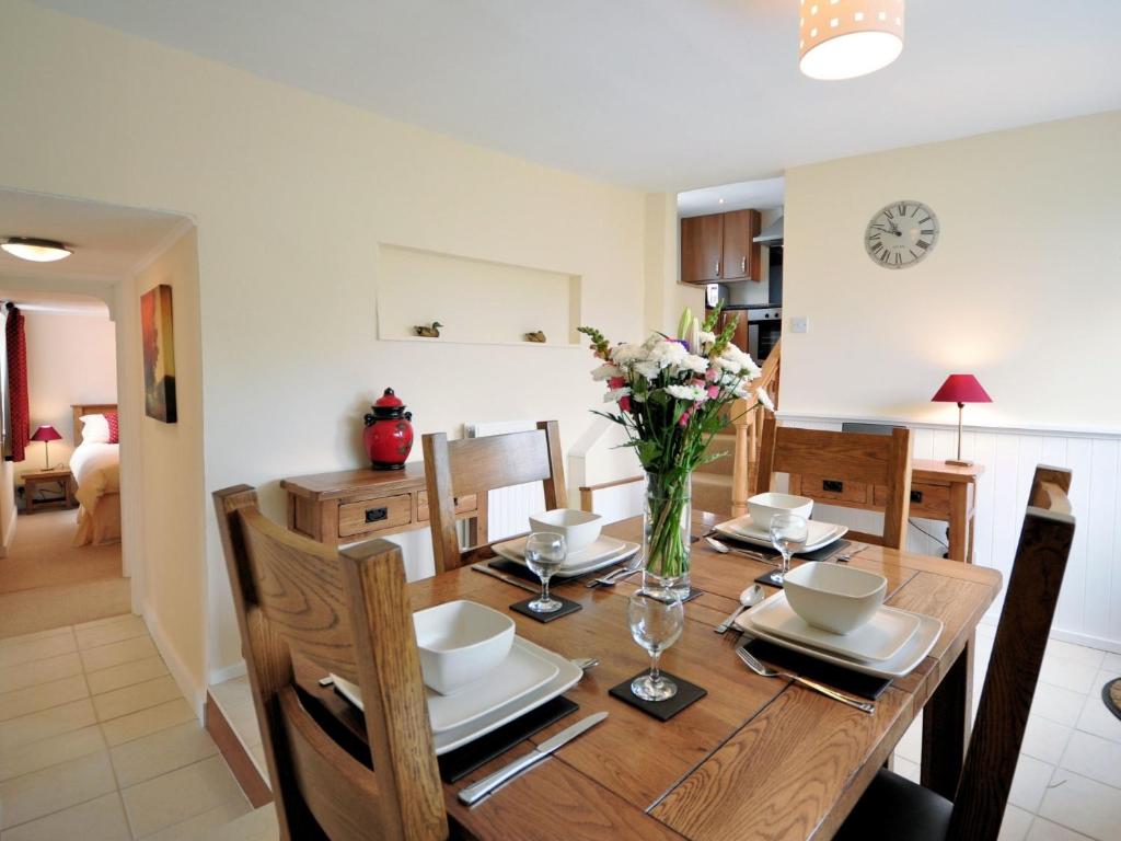 a dining room table with a vase of flowers on it at 2 Bed in Clovelly FORDM in Woolfardisworthy