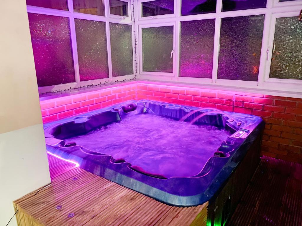 a purple hot tub in a room with windows at Big House with En-suites a Big garden and Hot-tub near TOWER BRIDGE in London