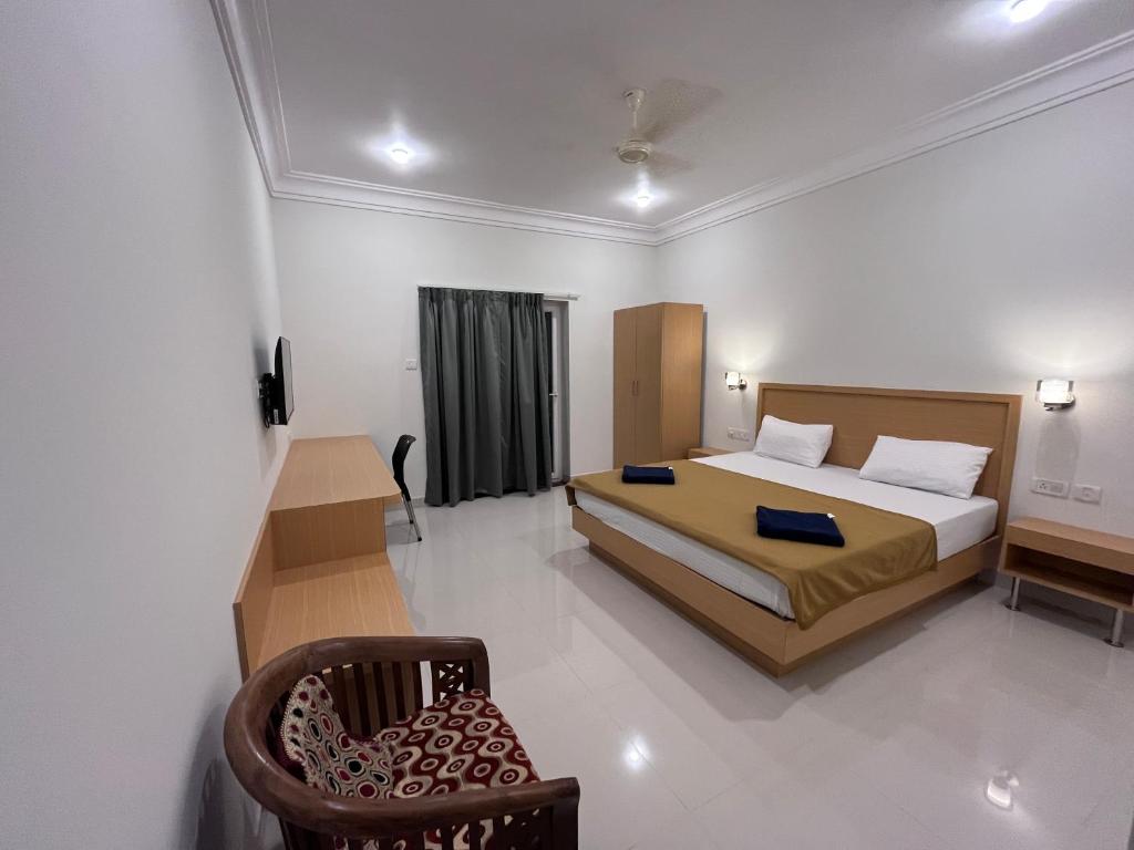 a bedroom with a bed and a chair in it at Morjim Sunset Guesthouse- Apartments with Kitchen in Morjim