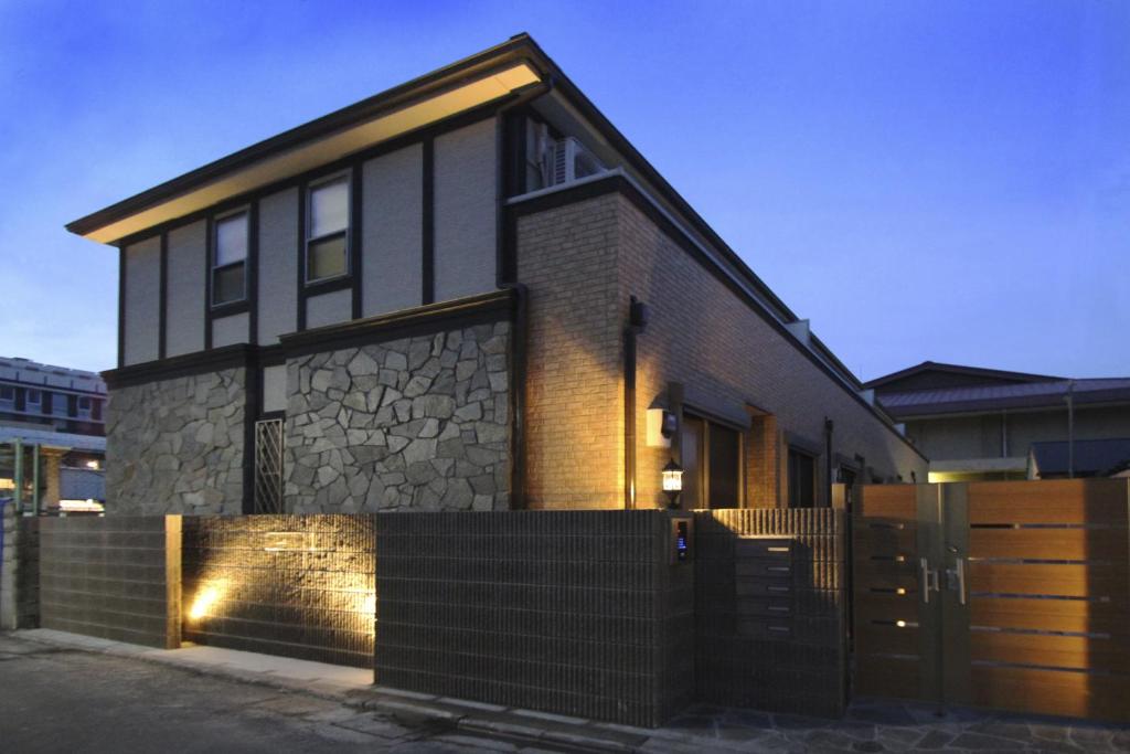 a black house with a stone facade with a gate at Acqua Pulita in Kyoto