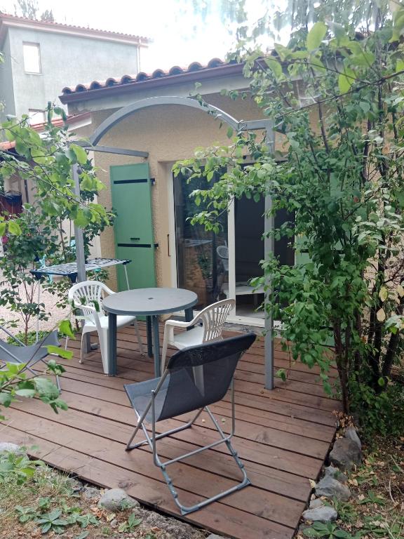 una terraza de madera con mesa y sillas. en Digne vallon des sources, en Digne-les-Bains