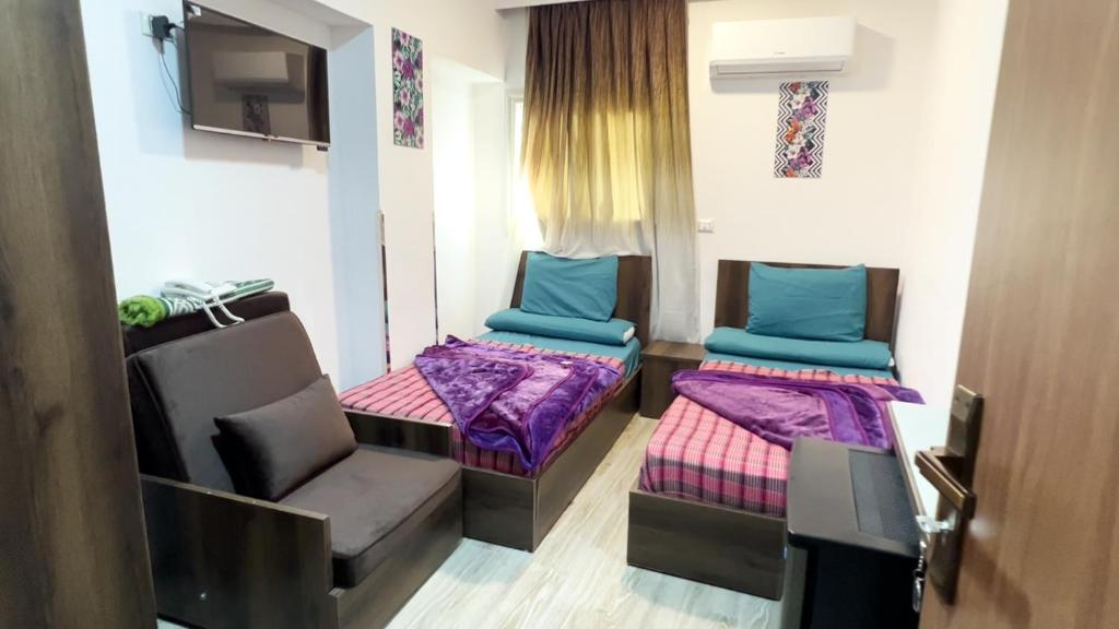 a room with two beds and a chair and a tv at فندق أجياد Agyad Hotel in Asyut