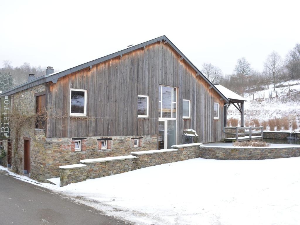 a barn with snow on the ground in front of it at Villa with hot tub and sauna in Bièvre