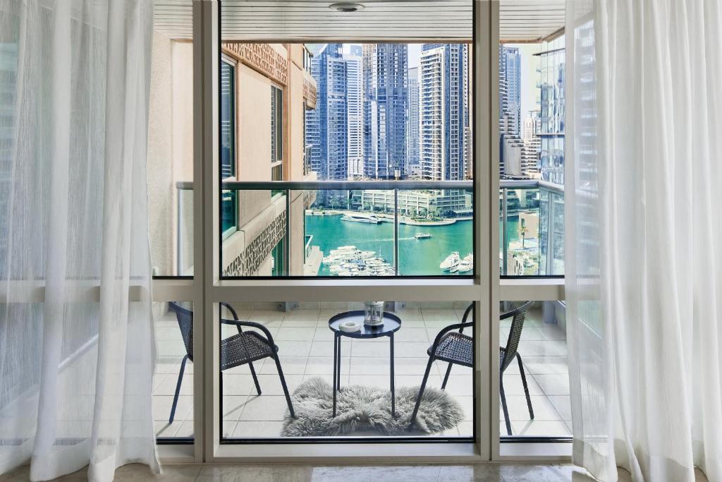 a balcony with two chairs and a view of a city at Luxury Dubai Marina Views On Marina Walk Waterfront 3 Bed Property in Dubai
