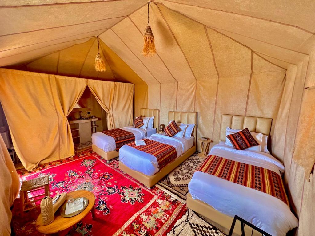 a group of four beds in a tent at Desert Sahara Luxury Camp in Merzouga